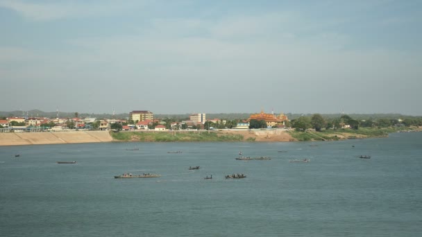 Upper view of the Mekong river and fishermen 's boats lifting their large nets out of water: Riverside town in the background — стоковое видео