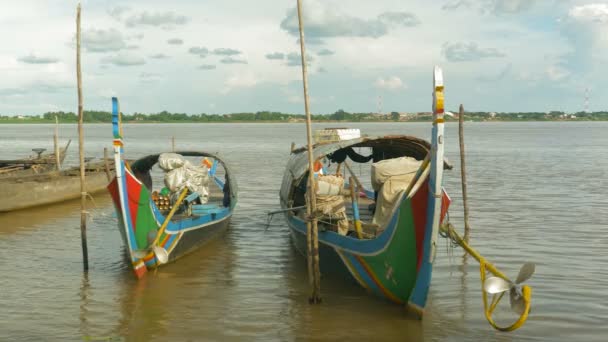 Perto de um par de barcos de pesca tradicionais coloridos mantém lado a lado com paus de bambu na borda do rio — Vídeo de Stock