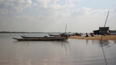 Nehir kıyısında oturan ve elle balık ağları tamir sabit dugout kano ve balıkçılar için Riverside görünümü