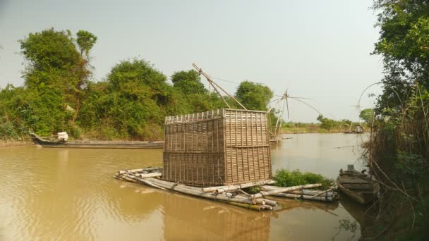 Bamboo fish crate emerging from river at low tide; Chinese fishing net behind — Stock Video