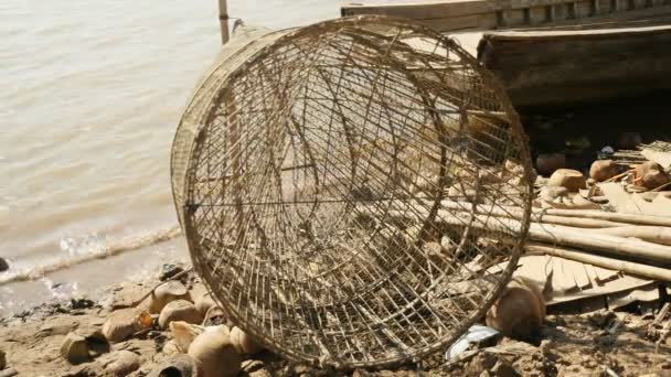 Primer plano de la trampa de pescado hecha a mano hecha de bambú colocada en la orilla del río — Vídeos de Stock