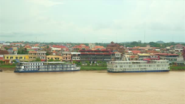 Bateaux de croisière amarrés le long de la ville riveraine sous un ciel nuageux — Video