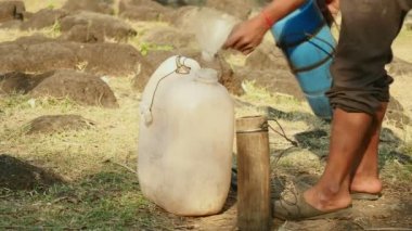  Yakın çekim toddy uzantılar üzerinde taze dökme palm su bir huni kullanarak bir plastik bidon içinde hasat