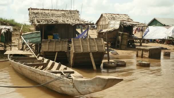 Pequenas casas de palafitas de pescadores com canoa, caixas de peixe e galinhas na beira do rio — Vídeo de Stock