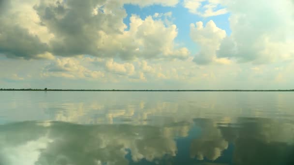 Nuvens brancas e cinzentas no céu azul refletidas na água do lago — Vídeo de Stock