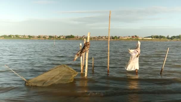 Rede de gaiola de peixe mantém com paus de bambu na borda do rio em um dia ventoso (close-up  ) — Vídeo de Stock