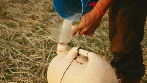 Close-up em toddy-tapper derramando seiva de palma recém-colhida em um jarro de plástico usando um funil — Vídeo de Stock