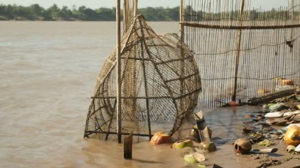 Trampa de pescado hecha a mano hecha de bambú tendida en aguas poco profundas junto al río en un día ventoso — Vídeo de stock