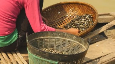 Nehir istiridye kayalar bambu sepet içinde çözmek ve bir havzasında (yakın tutarak kadın )