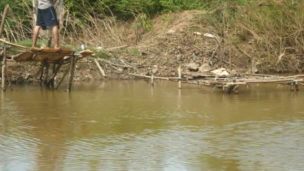 Рибалка кидає сітку в ставок з невеликої дерев'яної платформи . — стокове відео