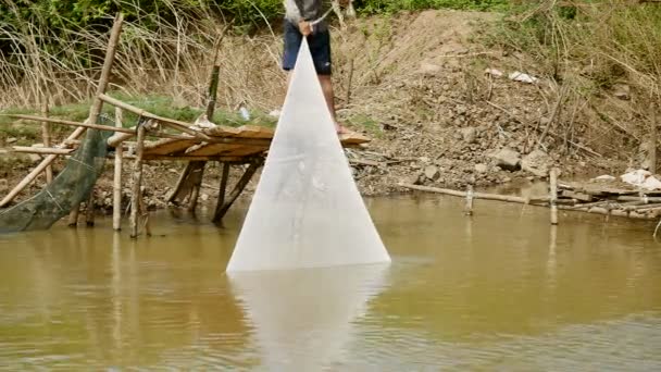 Rybář tahá síť z vody stojící na platformě malé bambusové. — Stock video