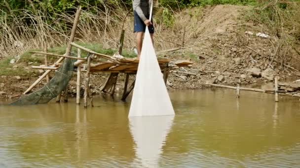 Fisherman is pulling the fishing net inside water towards himself — Stock Video