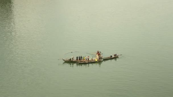 Vue supérieure sur les pêcheurs à bord de petits bateaux soulevant ensemble un grand filet hors de l'eau — Video