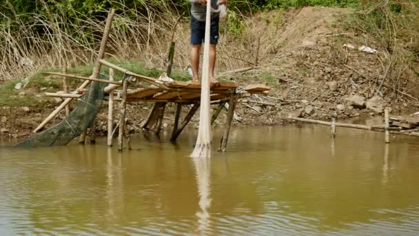Рыбак вытаскивает сеть удерживая рыб из воды — стоковое видео