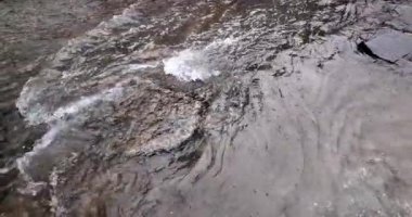 Yağmur damlaları bulanık, akan suda dalgalanır ve beyaz köpük oluşturur. (yavaş çekimde ) 