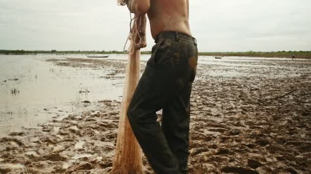 Ground-level view on fisher standing up by the river looking for a good place to cast the net — Stock Video