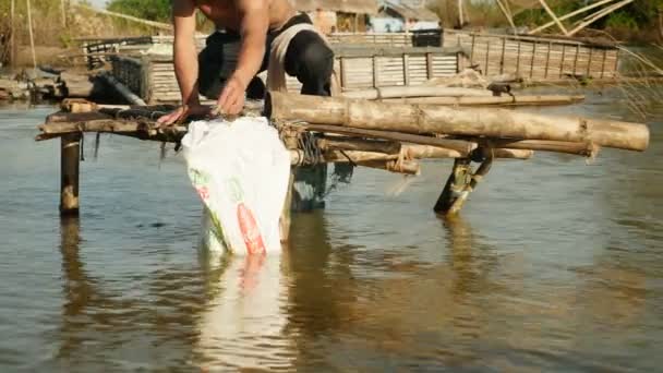 Pescador sacando pescado enredado de su red a mano y guardarlo en una bolsa de plástico (de cerca  ) — Vídeo de stock