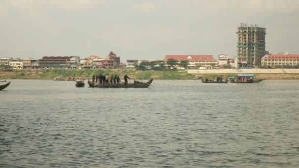 Pêcheurs dans des bateaux soulevant un grand filet hors de l'eau ; ville riveraine en arrière-plan — Video