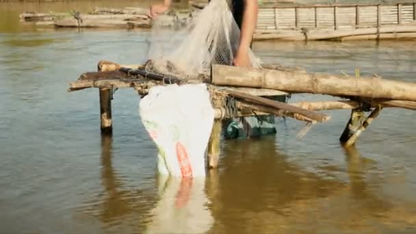 Pescador sacando pescado enredado de su red a mano y guardarlo en una bolsa de plástico (de cerca  ) — Vídeos de Stock