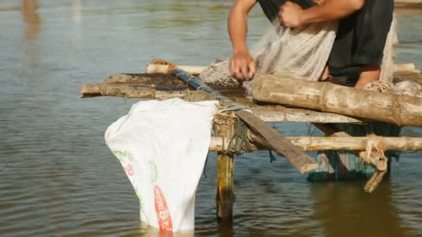 Pescador sacando pescado enredado de su red a mano y guardarlo en una bolsa de plástico — Vídeo de stock