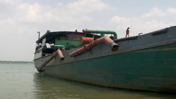 Vista laterale di una vecchia barca di dragaggio legata alla riva del fiume, sezioni di tubi tenute fuori dall'acqua — Video Stock