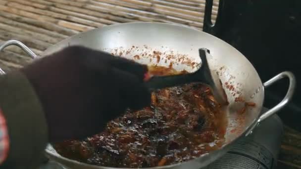 Woman stirring deep frying grasshoppers inside a wok using a metal spatula — Stock Video