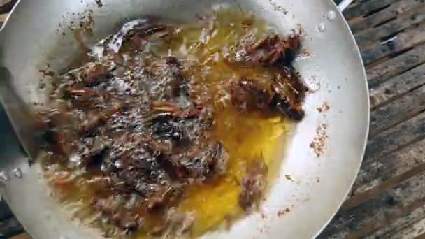 Kvinna under omrörning djupa stekning gräshoppor inuti en wok med en metall spatel — Stockvideo