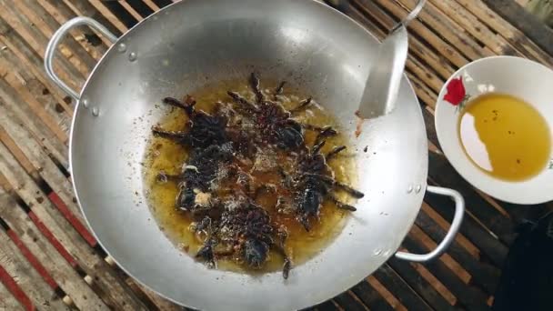 Woman turning over deep frying tarantulas inside a wok using a metal spatula — Αρχείο Βίντεο