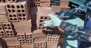 Kırmızı tuğlaları istifleyen bir işçiyi kapatın..