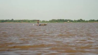 arkasında su yoluyla bir balıkçı ağı çekerken nehir üzerinde balıkçı kürek