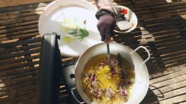 Metal maşa kullanarak tavadan kızarmış tarantulaları alıp tabağa koyan bir kadın.