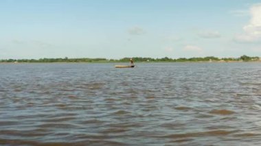 arkasında su yoluyla bir balıkçı ağı çekerken nehir üzerinde balıkçı kürek