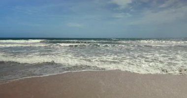 Kumlu kıyı şeridinde köpüklü dalgalar süzülüyor. (yavaş çekimde)