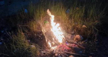 Kuru çimenlerin arasında yanan plastiğin yakın görüntüsü.