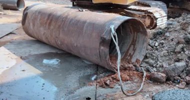 Büyük, paslı, metal bir fıçıya yakın bir yerde ıslak kil bir inşaat sahasına dökülüyor..