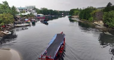 Geleneksel Kamboçya motorbotu, mangrov kaplı bir nehirde bir köprünün altından çıkıyor..