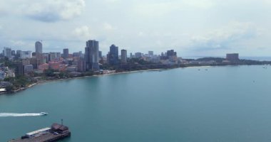 Arka planda Sihanoukville silueti olan turkuaz bir denizde uzun bir yolculuk yapan bir sürat teknesinin hava görüntüsü..