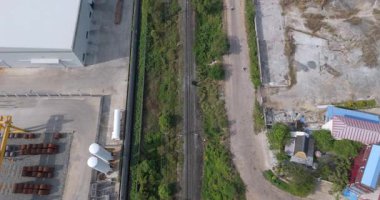 Endüstriyel bir depo, yeşillik ve tozlu bir yol arasında uzanan....