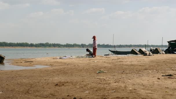 Fisher sitting on the riverbank and mending a fishing net by hand — Stock Footage Fisher sitting on the riverbank and mending a fishing net by hand Royalty Free Stock Footage