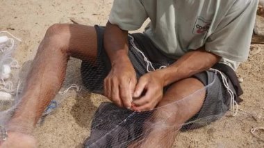 Kampong - Kamboçya - 03 - 02 - 2015: Nehir kıyısında oturup ağları elle onaran bir balıkçıya yakın çekim