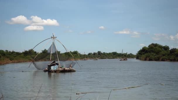 Distância vista para o pescador usando uma rede de mão para capturar peixes fora de uma rede de pesca chinesa — Vídeo de Stock