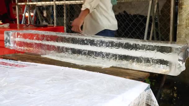 Vendedor de hielo mover un gran bloque de hielo utilizando un gancho y pre-corte pequeños bloques de hielo fuera de ella — Vídeos de Stock