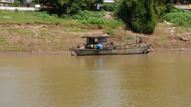 Antiguo barco de dragado de madera atado en la orilla del río (disparado desde el barco en movimiento ) — Vídeos de Stock