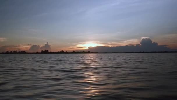 Vue depuis un petit bateau à moteur lors d'une balade sur un lac au coucher du soleil sous un ciel dégagé — Video