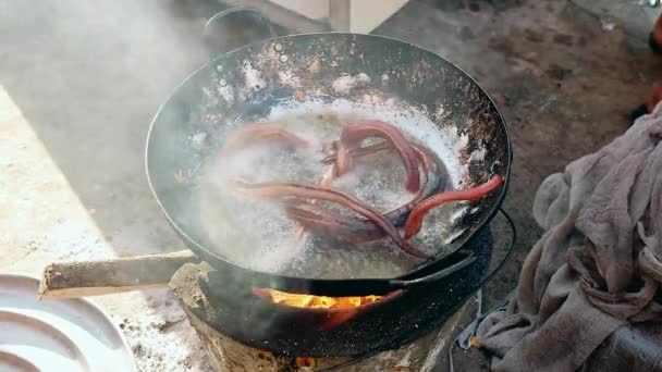 Woman plunging dead snakes into boiling oil for cooking — Stock Video