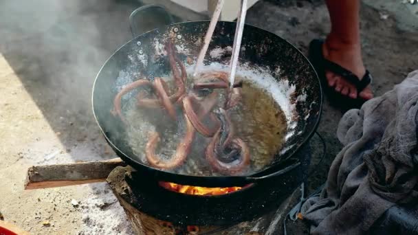 Agitar serpientes fritas dentro de un wok usando unas pinzas metálicas — Vídeo de stock
