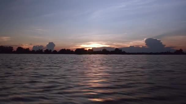 Vue depuis un petit bateau à moteur lors d'une balade sur un lac au coucher du soleil sous un ciel dégagé — Video