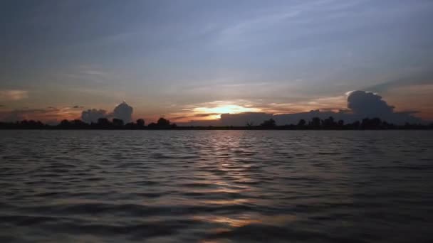 Uitzicht vanaf een kleine motorboot tijdens een ritje op een meer bij zonsondergang onder heldere hemel — Stockvideo