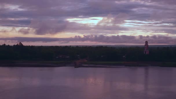Ampi lividi viola cielo tramonto che si riflette sul fiume; Torre di avvistamento che sale lungo la riva del fiume come sfondo — Video Stock