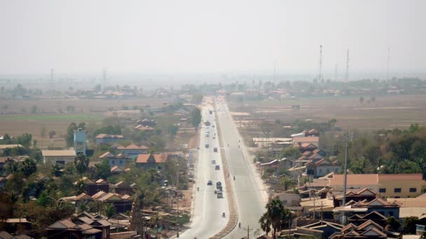 Вид зверху головної дороги, що проходить через маленьке містечко під пиляним сірим небом — стокове відео